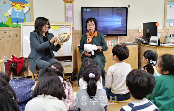 홍성의 동화구연 지도사 이희자 씨가 손인형을 든 채 동화를 들려주자 아이들이 이야기에 몰입하며 듣고 있다. 사진 우측에 앉아 있는 이가 이희자 씨다.