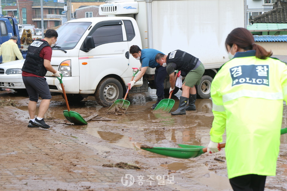 도로가에 흘러온 토사와 쓰레기더미를 치우는 예산경찰서 직원들 모습.