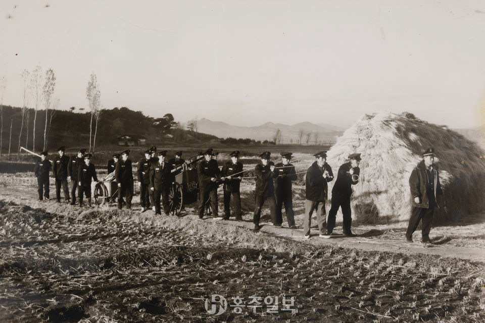 화재진압 훈련을 위해 밧줄을 이용해 완용펌프를 끌고 리어카에 장비를 싣고 이동하는 1960년대 의용소방대원들(예산군 추정).