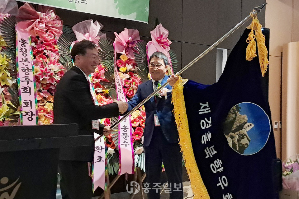 김명환 재경홍북읍향우회 이임회장(오른쪽)이 박성범 취임회장에게 향우회기를 전해주고 있는 모습.