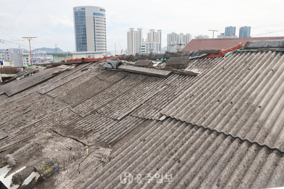 부산 동구 수정동의 슬레이트 지붕과 고층 빌딩이 대조적이다.