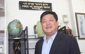 이상범 재경금마면민회장이 가게 안에 자신이 좋아하는 성경구절이 적힌 액자 앞에서 기념사진을 촬영하고 있다.