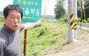 우종설 씨가 마을진입로에서 장곡면 소재지 방면으로 굽이진 도로를 가리키며 사고 예방을 위한 대책을 호소하고 있다.