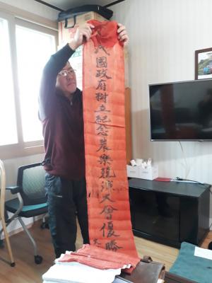 최정권 씨가 1946년 정부수립 기념으로 열린 전국농악경연대회에 참여해 받은 우수상 기념 휘호를 펼쳐 보여주고 있다.