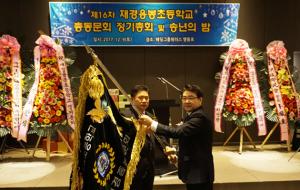 왼쪽부터 이육환 취임회장이 이종섭 이임회장에게 재경동문회기를 전달받고 있다.