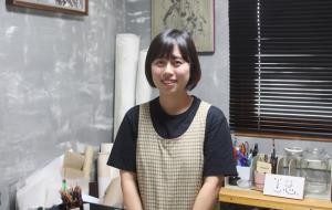 채정옥 작가가 자신의 작업실 안에서 밝게 웃고 있다.