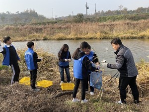 학생들이 직접 만든 EM흙공을 상지천에 던지고 있다. 던져진 EM흙공은 각종 유해물질로 오염된 하천을 살리고, 그곳에서 서식하고 있는 동식물의 생태환경도 회복하는 것으로 알려졌다