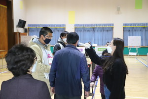 선관위 직원의 안내로 간단한 코로나19 감염예방을 위한 발열체크를 후 투표절차를 밟고 있는 유권자들. 지난 11일 홍성군 장곡면사전투표소에서 사전투표하고 있는 유권자들의 모습.