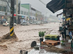 예산시장이 물에 잠겼다. 한 가게 주인이 황급히 상황을 수습하려 하고있다.