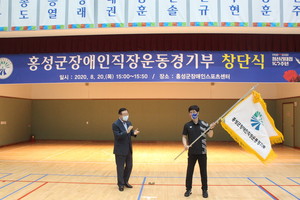휠체어펜싱 유승열 감독이&nbsp;김석환 군수로부터 전달받은 단기를 힘차게 흔들고 있다.