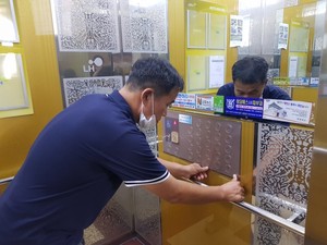 아파트 단지 내 엘리베이터에 향균필름을 부착하고 있다.