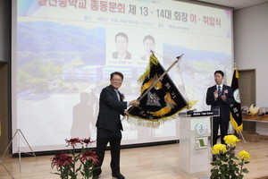 총동문회기 인계 인수를 하고 있는 김영동 이임회장이 힘차게 대회기를 세 번 흔들고 있다.