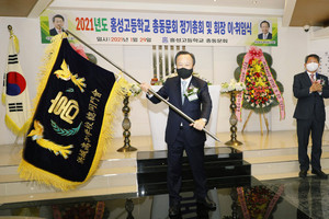 홍성고등학교총동문회 홍일표 취임회장이 남기웅 이임회장에게 전달받은 동문회기를 흔들어 보이고 있다.