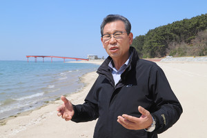 정상운 남당항 축제추진위원장 뒤로 신축된 전망대와 깨끗한 모래사장이 보인다.