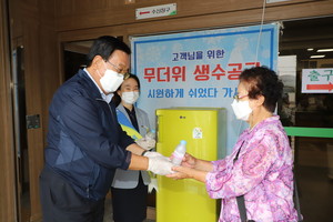 홍성농협 정해명 조합장(왼쪽)이 무더위 극복을 위한 폭염냉장고를 본점 객장에 설치하고 농협을 방문한 지역주민에게 시원한 얼음물을 전달하고 있다. 