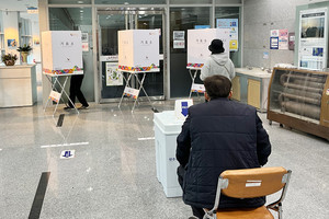 투표안내원이 투표지를 받은 유권자에 빈 기표소를 안내하고 있다.