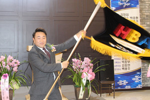 김창섭 취임회장이 노승천 이임회장으로부터 전달받은 협회기를 흔들어보이고 있다.