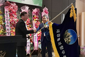 김명환 재경홍북읍향우회 이임회장(오른쪽)이 박성범 취임회장에게 향우회기를 전해주고 있는 모습.