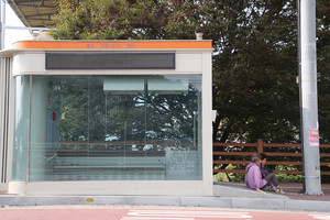 스마트버스승강장의 출입구 자동문이 고장나 바닥에 앉아 버스를 기다리고 있는 어르신들.