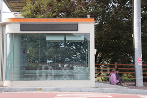 스마트버스승강장의 출입구 자동문이 고장나 바닥에 앉아 버스를 기다리고 있는 어르신들.