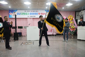 이계석 취임회장이 김경환 이임회장으로부터 전달받은 총동창회기를 흔들어 보이고 있다.