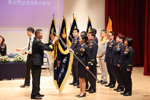 예산소방서 전영수 서장이 예산소방서의용소방대연합회기를 인계하며 수치(綬幟)를 달아주고 있다.