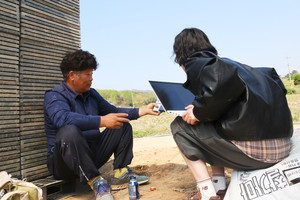 모내기를 준비 중인 고영섭 회장이 모판에 기대어 인터뷰 중, 기자에게 벼농사 장면을 보여주고 있다. 이정은 기자
