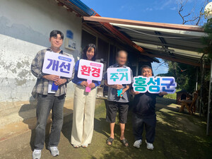 치매어르신과 희망복지팀이 ’주거환경개선‘ 팻말을 들고 기념촬영을 하고 있다.