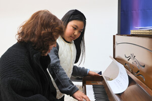 3학년 이지안 학생이 체험자에게 피아노를 가르치고 있다.