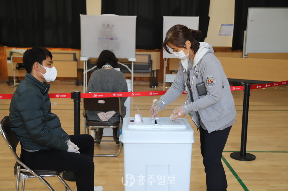 홍동초등학교 홍예관에 마련된 홍동면사전투표소를 찾은 유권자들이 기표소에 기표한 후 투표함에 넣는 장면.