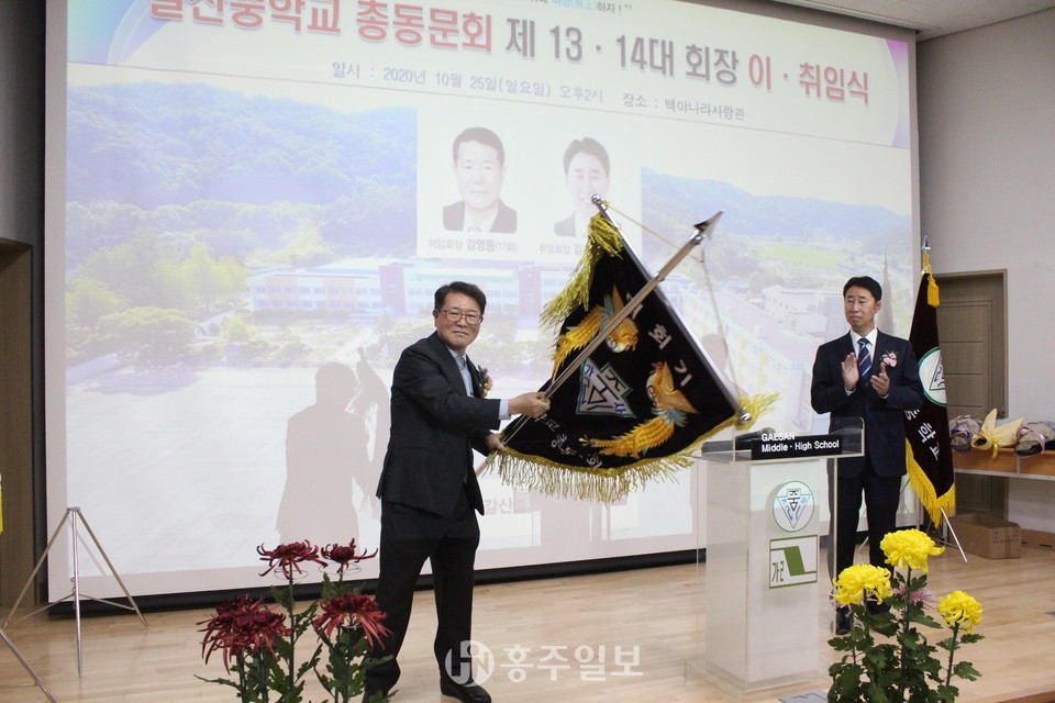 총동문회기 인계인수를 하고 있는 김영동 이임회장이 힘차게 대회기를 세 번 흔들고 있다.